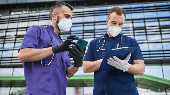 Two medical residents reviewing a document on a clipboard.
